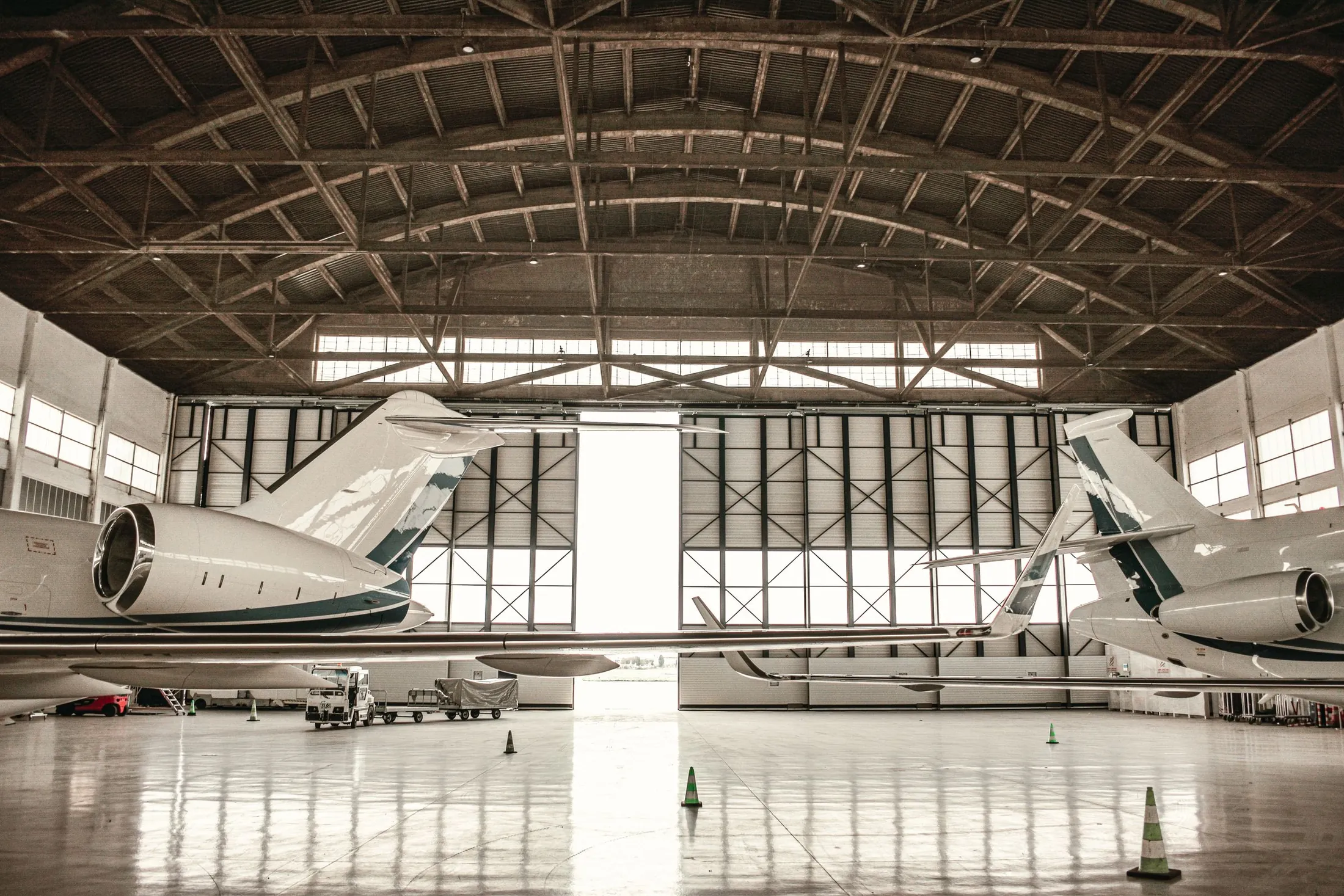 Two business jets parked inside a maintenance hangar