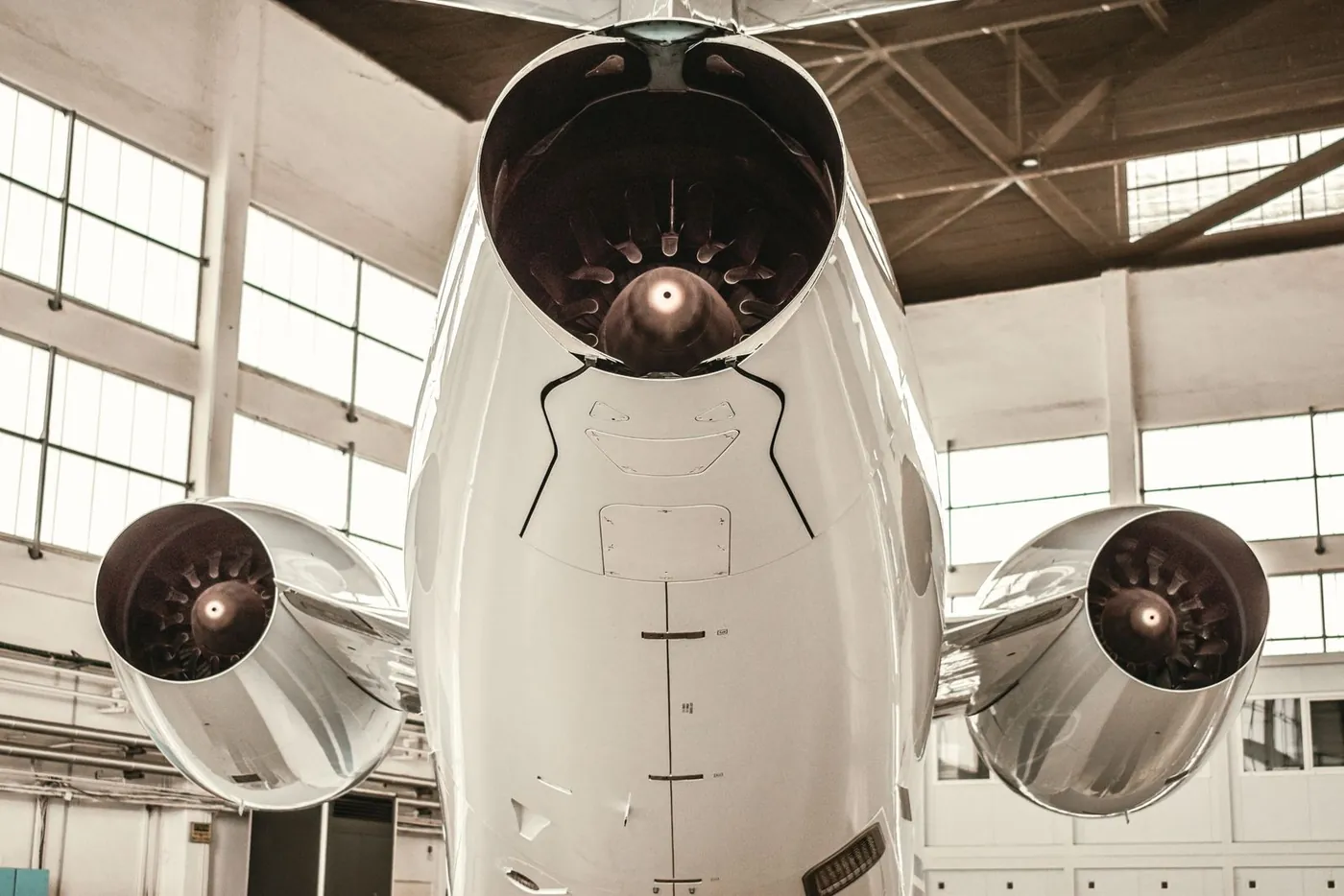 Three-engine business jet seen from below, showing fuselage panels and exterior finish